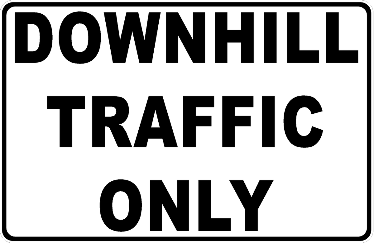 White rectangular sign with bold black “DOWNHILL TRAFFIC ONLY” lettering and a black border.