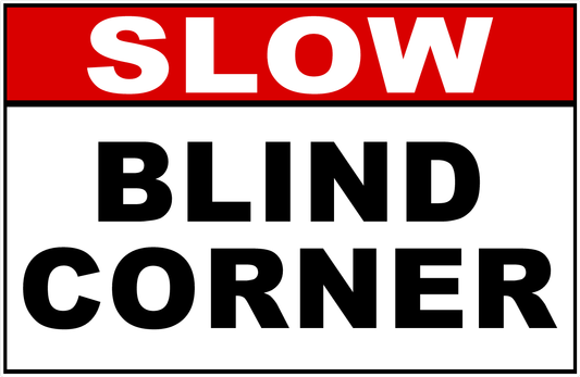 A rectangular warning sign with a red header reading 'SLOW' in white letters and large black text below reading 'BLIND CORNER' on a white background.